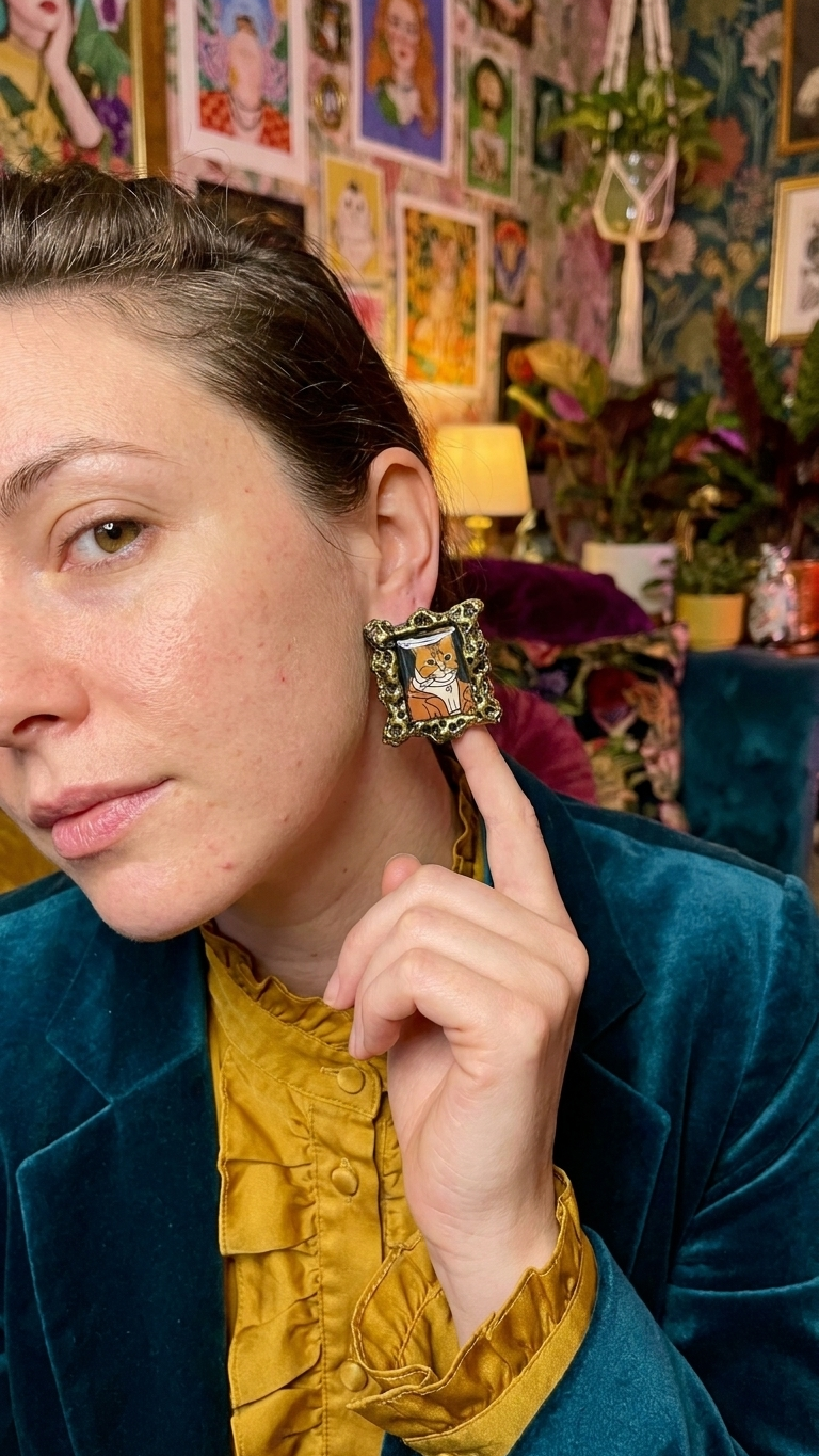 Cat portrait frame earring worn on ear with gallery wall background